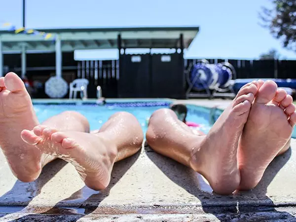 two people with their feet out of the pool resting on the side