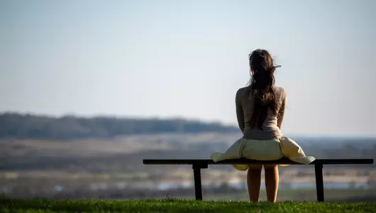 Woman sitting alone on bench outside.