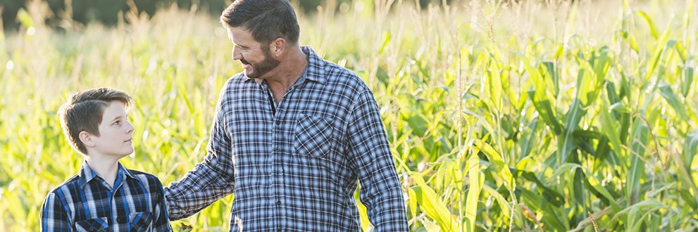 man talking to son in a corn field