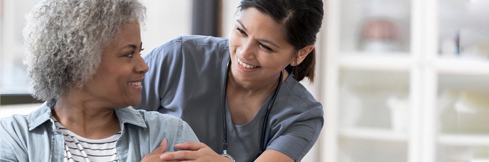 a medical assistant smiling with patient in a wheelchair
