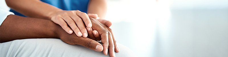 close up of a nurse's hand holding a patient's hand