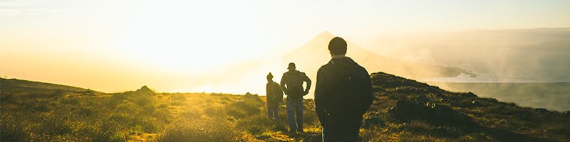 a group of people hiking into the sunset