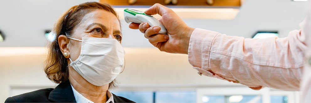 woman with mask on getting temperature checked
