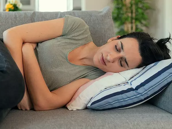 woman laying on a couch holding her stomach