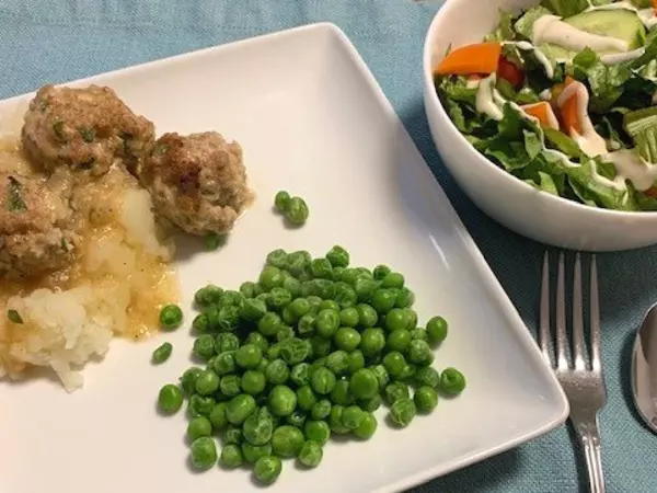 Turkey meatballs over mashed potatoes with a side of peas.