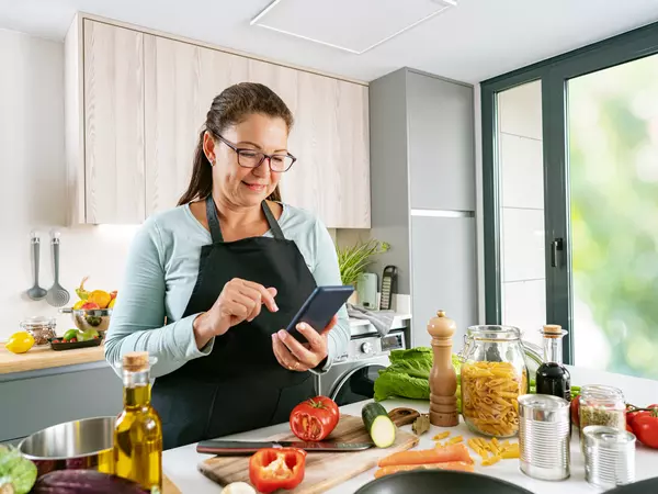 Woman cooking and using mobile phone in kitchen