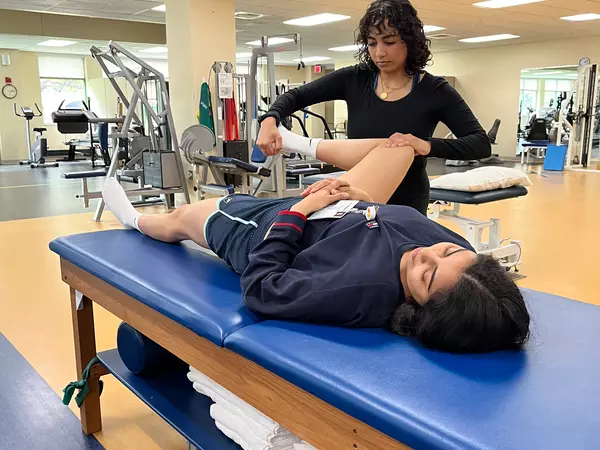 Medical student performing a knee exam on a patient