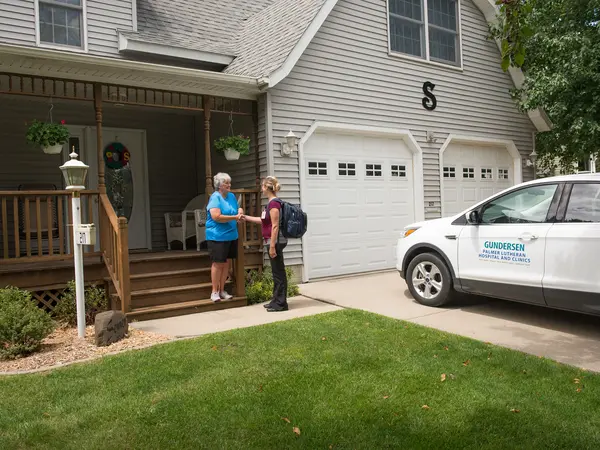 Home Health nurse and patient outside home.