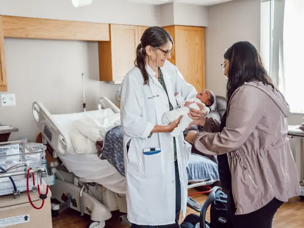 Doctor handing newborn to mother.