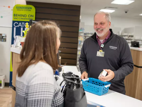 Gundersen pharmacist helping customer at checkout counter.
