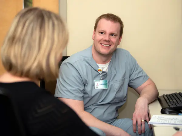 Pharmacist seated at desk helping patient.