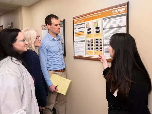 Four researchers looking at research poster on the wall and reviewing results.