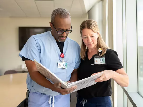 Gundersen clinical trial researchers Ezana Azene, MD, and Lisa Weinberger, RN, reviewing papers in file dressed in scrubs..jpg
