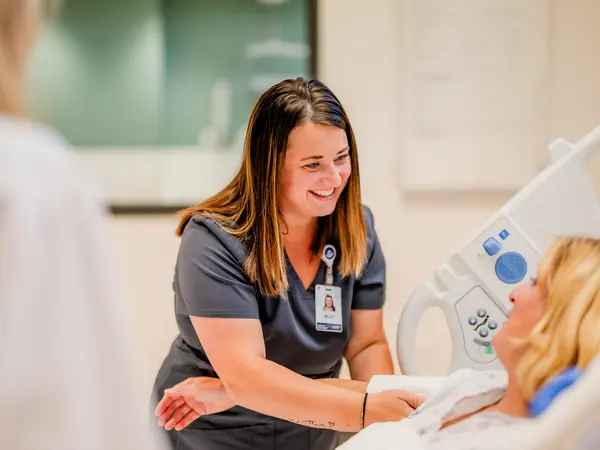 Medical assistant tending to elderly female patient in a hospital bed