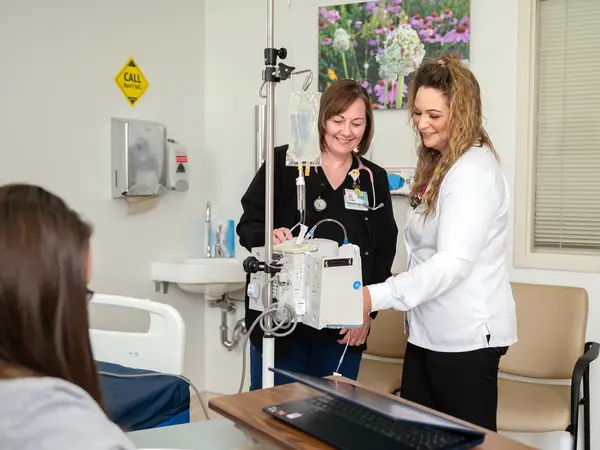 Registered nurse teaching new nurse about infusions.