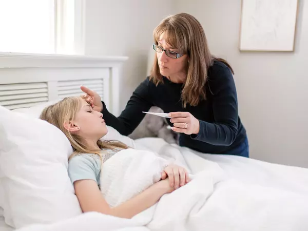 Concerned mother checking sick daughter's temperature.