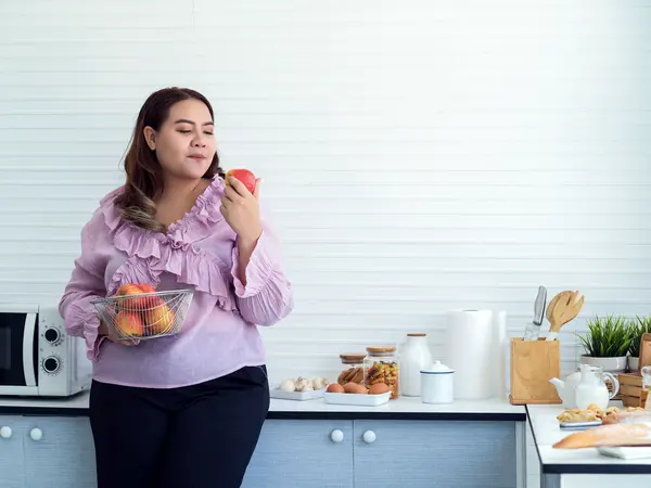 woman eating an apple in her kitchen at home