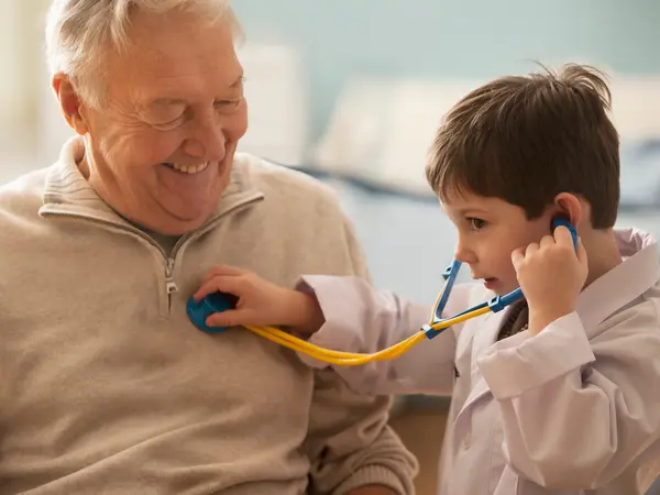 Caucasian boy listening to grandfather's heartbeat with stethoscope