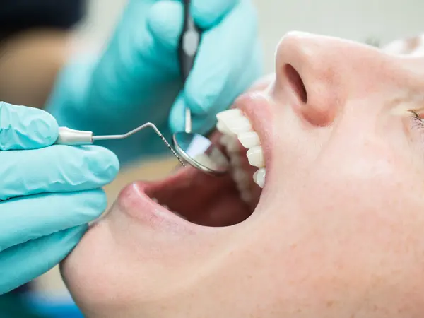 Young woman is with mouth open getting dental checkup in hospital.