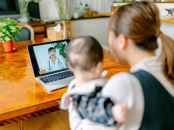 Mother with her baby video calling doctor from home