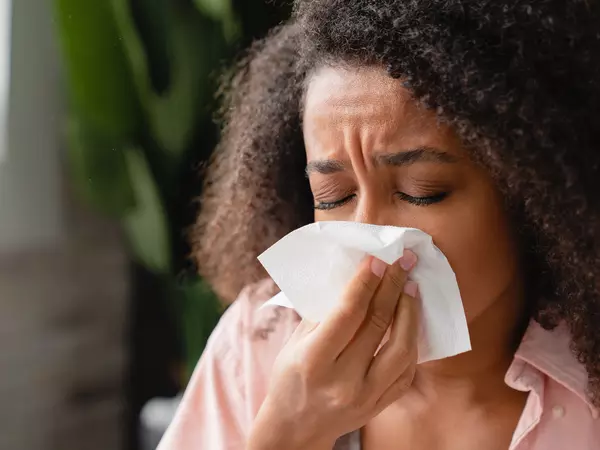 Sneezing ill young woman using tissue