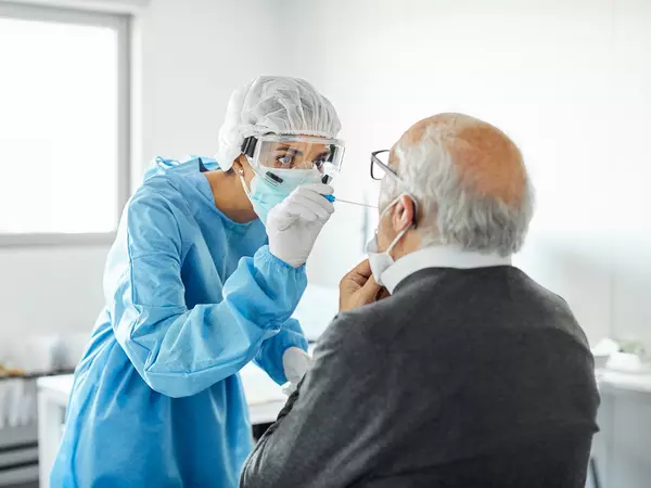 Doctor taking swab test sample of elderly patient