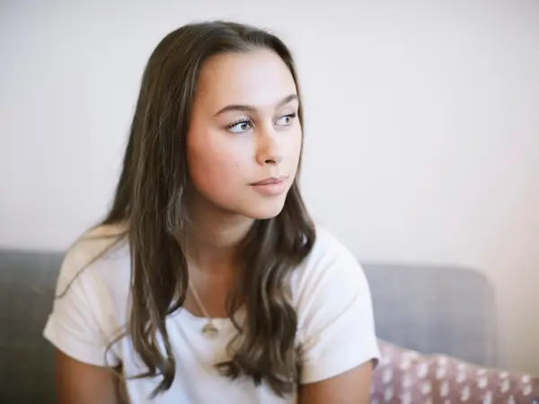Thoughtful teenage girl sitting at wellness center