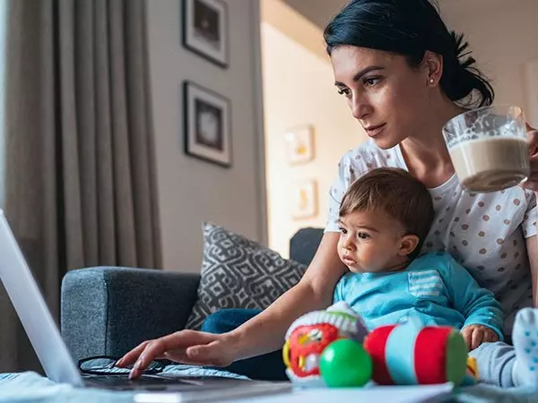 mother with baby on lap looking at laptop