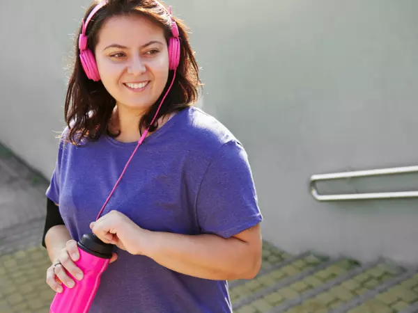 woman listening to music on headphones holding a water bottle