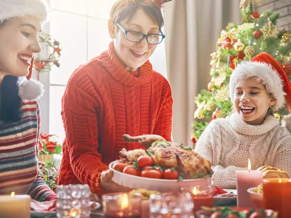eating well during the holidays - family sitting at a table about to eat a holiday dinner.'