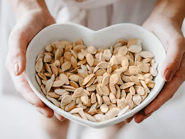 Woman holding a heart shaped bowl of roasted pumpkin seeds