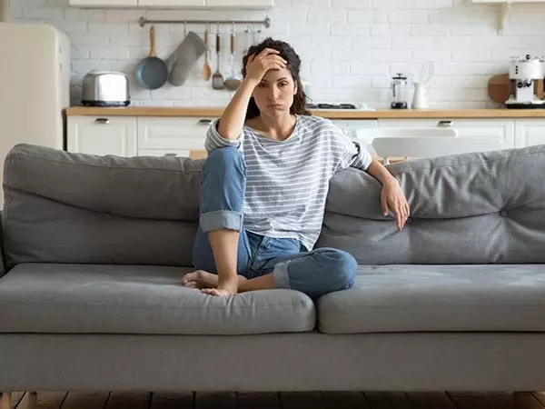 woman looking stressed sitting on her couch