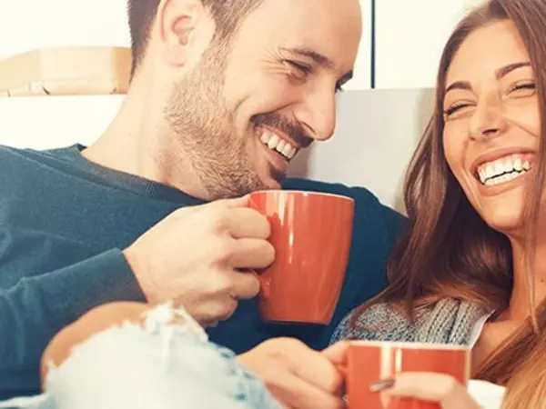 a couple smiling drinking coffee