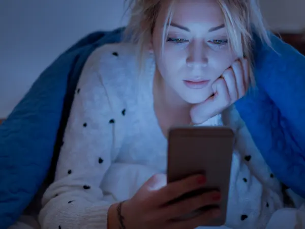 woman scrolling on smart phone at night in the dark