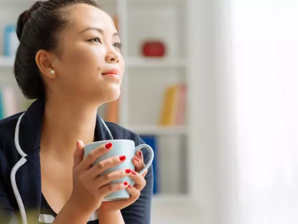 woman looking off into distance holding a coffee cup