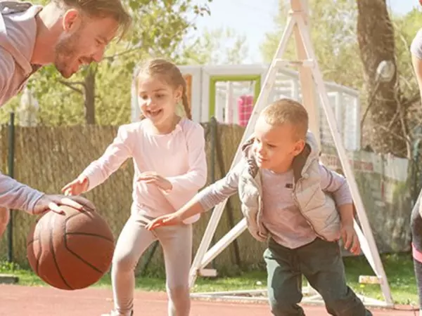 two parents playing basketball with children