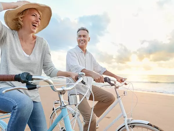 man and woman riding bikes on beach