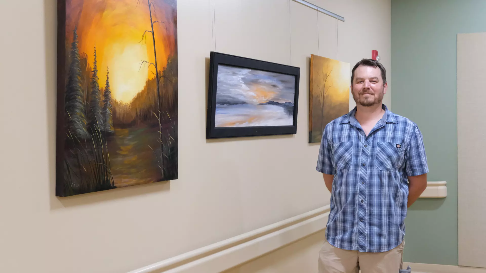 Local artist standing next to his painting in Boscobel hospital hallway.