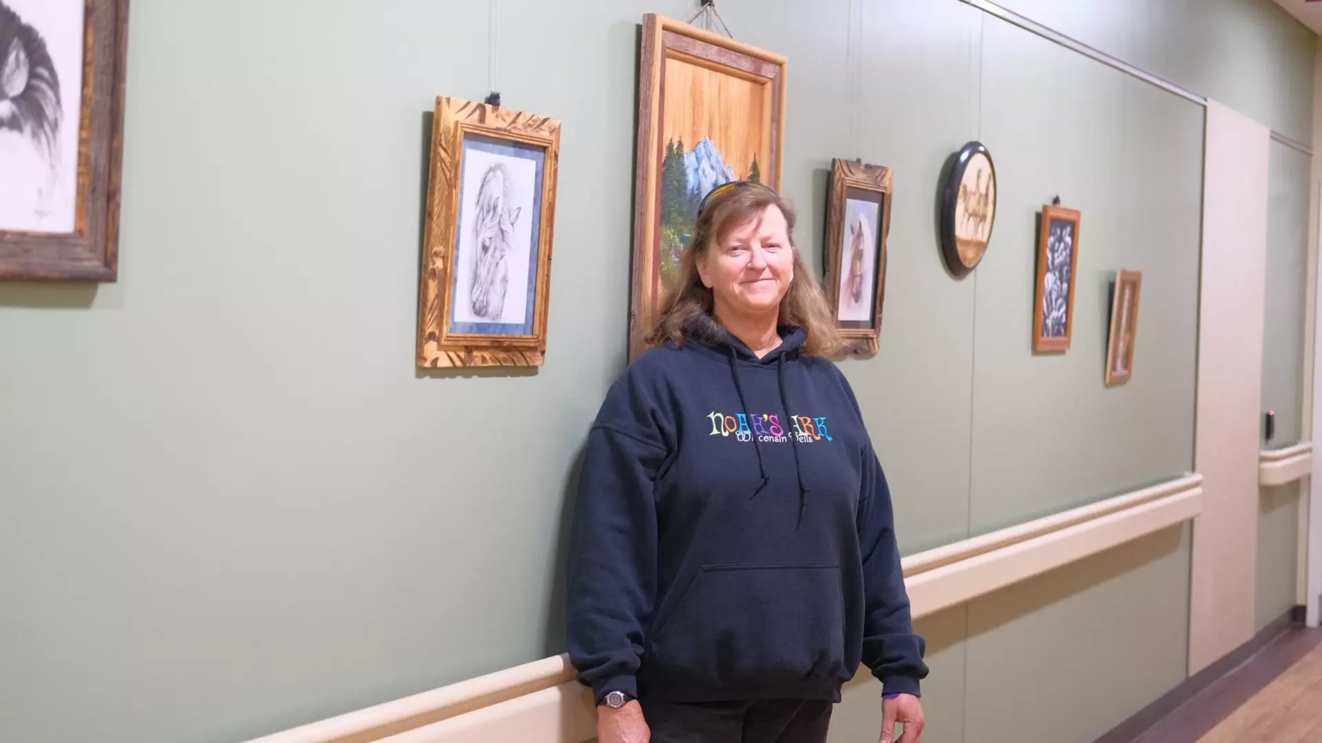 Woman standing next to artwork in hospital hallway.