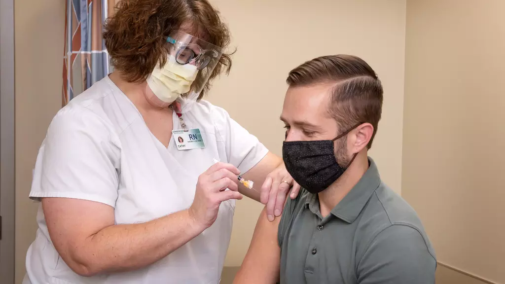 Nurse giving flu shot to a male patient.
