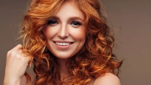 woman-smiling-with-curly-red-hair