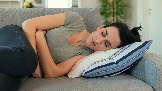 woman laying on a couch holding her stomach