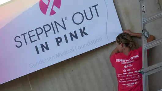 Woman hanging sign at steppin out in pink set up.
