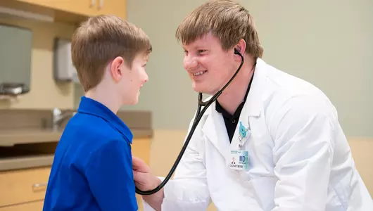Male doctor listening to child's heart beat.