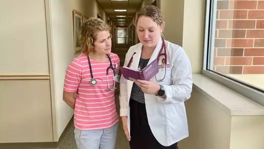 Medical student reviewing literature with doctor.