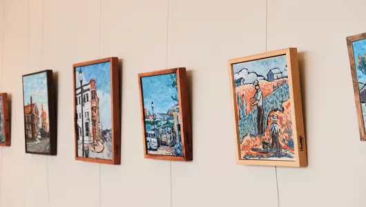 Paintings of rural scenery hanging in hospital art gallery.