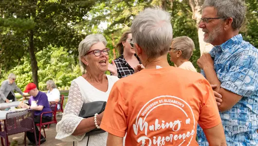 Woman talking to couple at picnic.