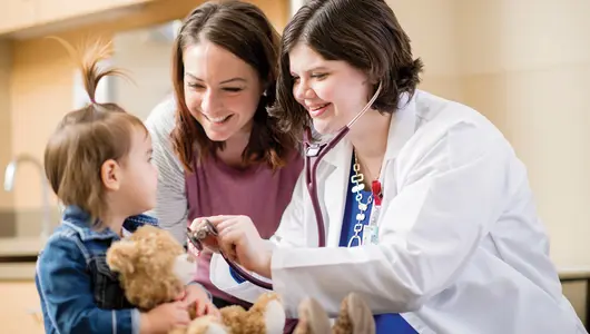Doctor and mother smiling at young girl.