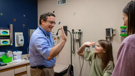Doctor giving young girl a high five after getting a vaccine.