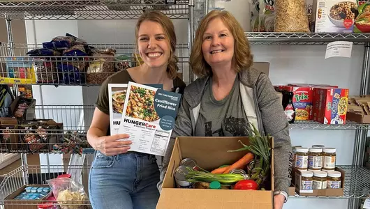Two women donating food to community food pantry.